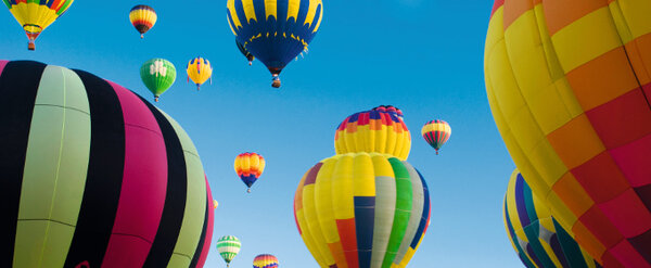Barviti leteči baloni na jasnem modren nebu